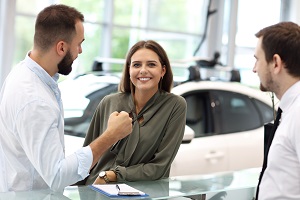 Woman at dealership with two salesman to find out if she can get a car
